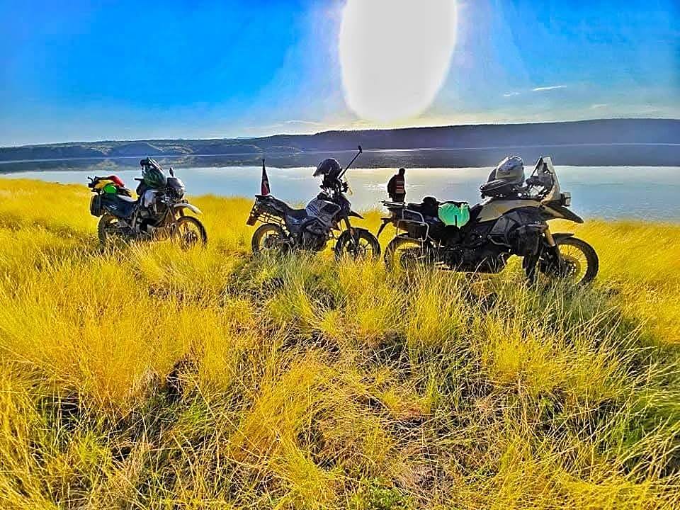 Adventure motorbikes parked in golden grass overlooking Lake Magadi
