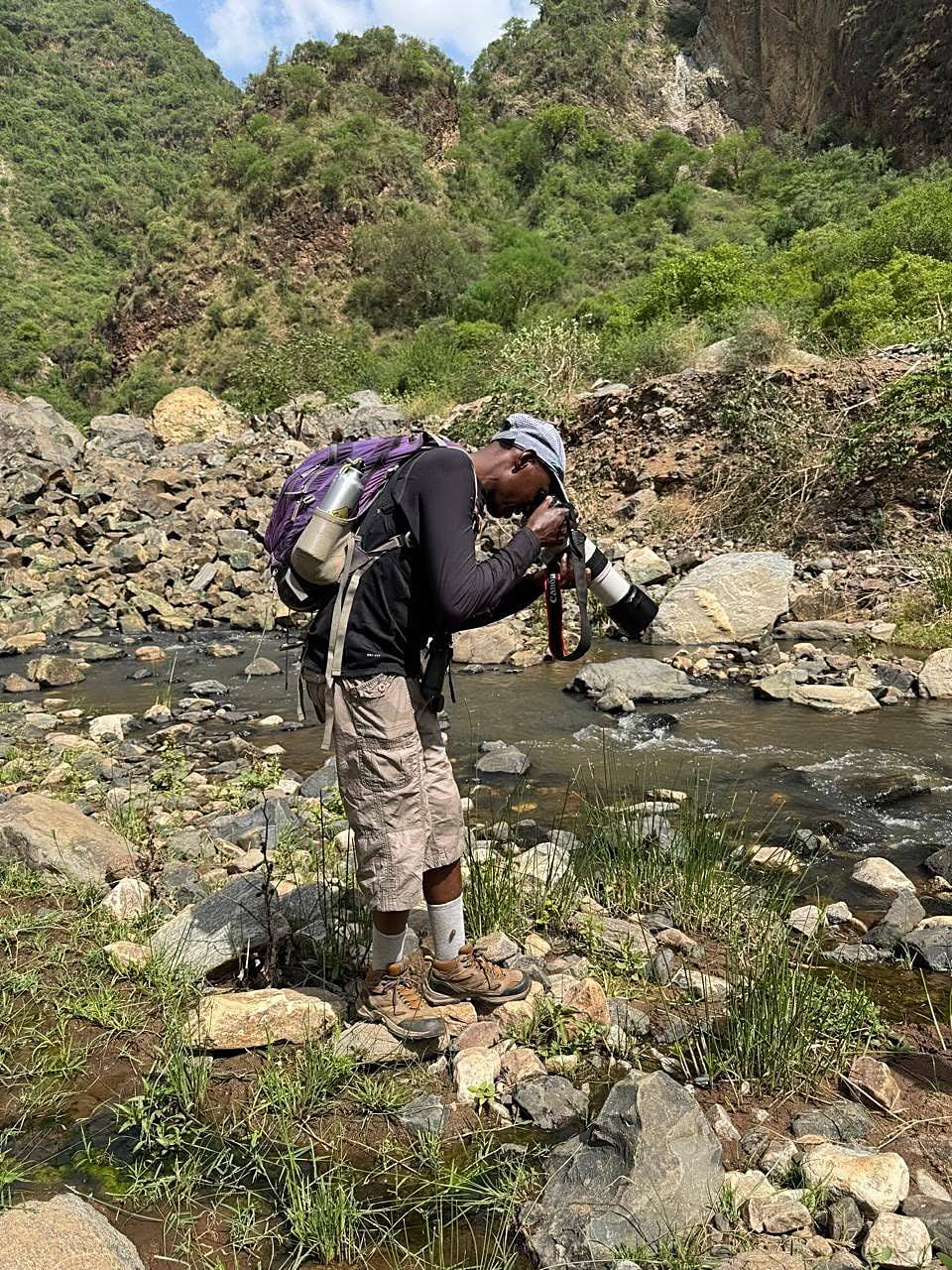A guide photographing the river from a rocky crossing point