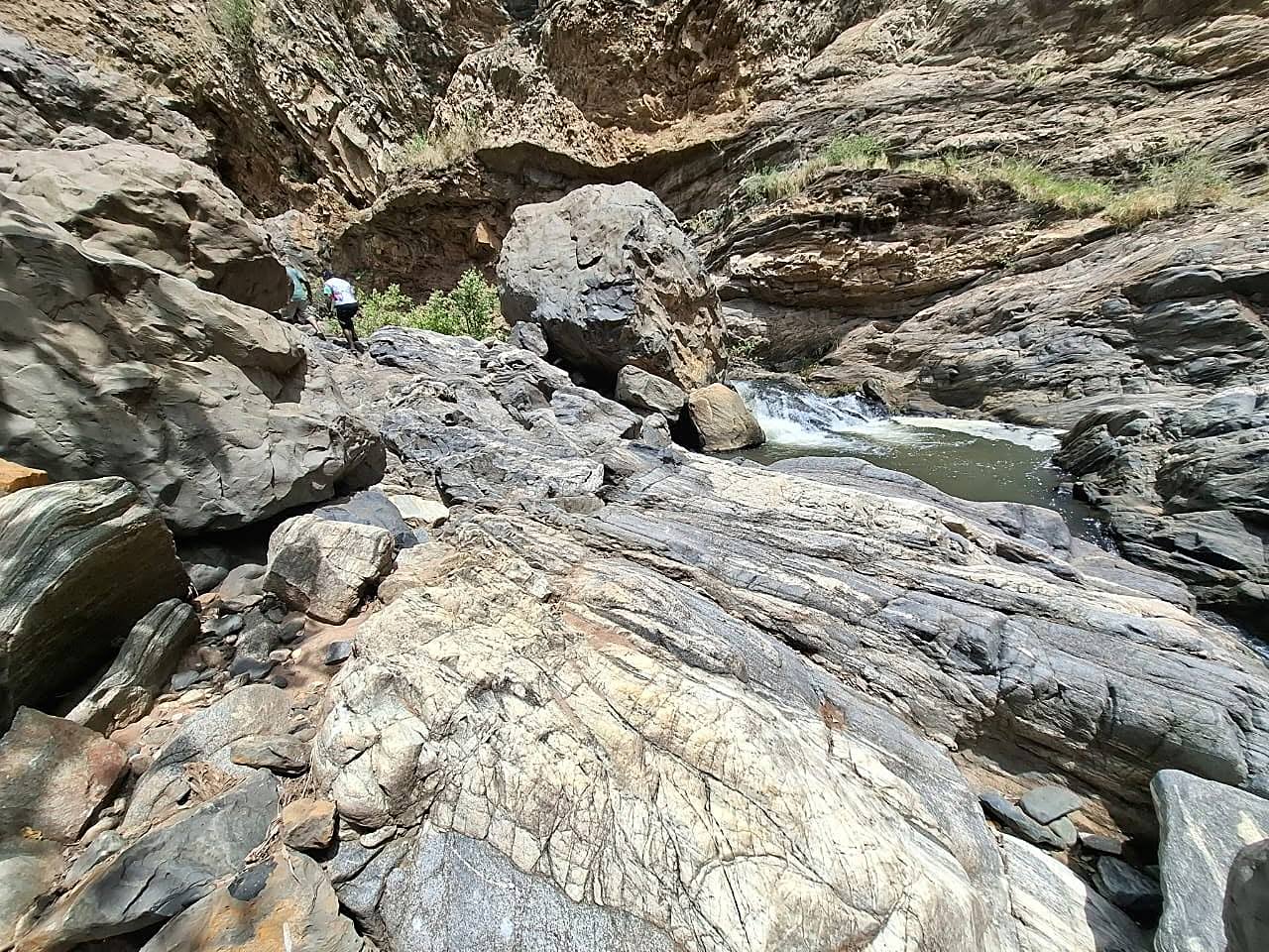 Hikers picking a path across boulders beside a river pool in the gorge